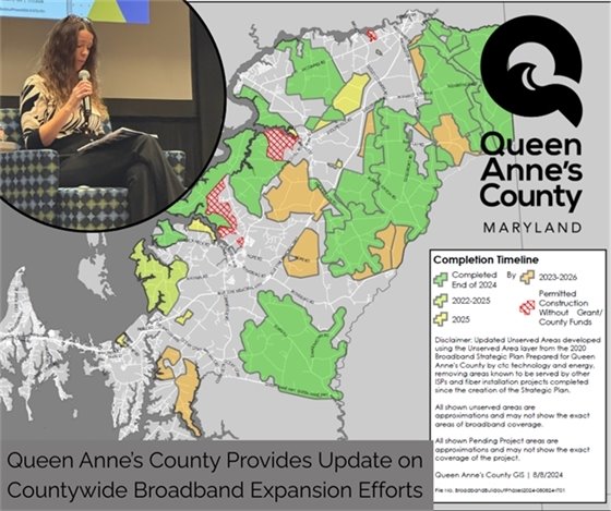 woman sitting in a chair with a microphone and a large map of the county