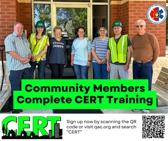 Row of people standing in front of the 911 center. Two are wearing hard hats and reflective vests.