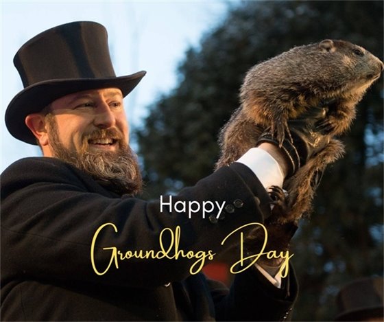 Man with a top hat holding a groundhog up