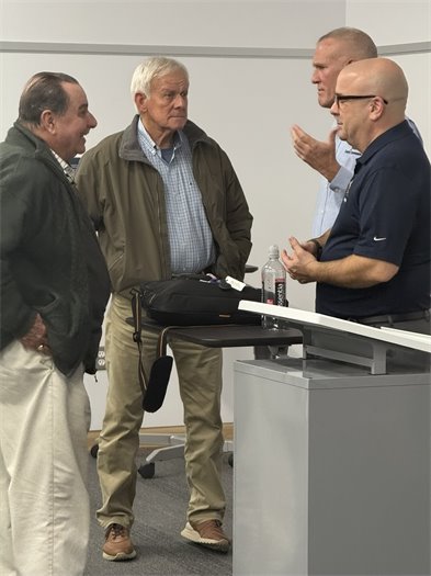 4 men standing up talking 