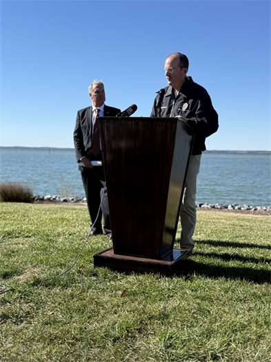 Man standing behind a podium in front of the water