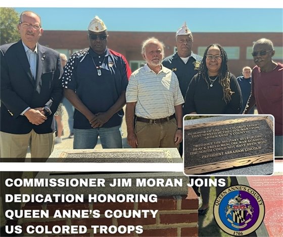 5 men and one woman standing in front of a plaque